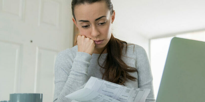 Woman paying her utility bills online and looking worried